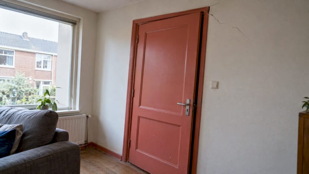 Scheefhangende binnendeur met scheur bij het kozijn