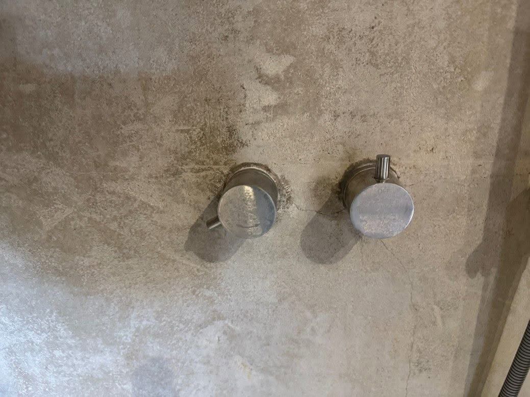 Detail van de wandafwerking rond de douchebediening